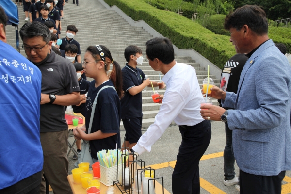 무더위에 학생들에게 차 봉사를 하고 있는 조병옥 군수와 최병호 회장.